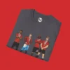 Close-up of charcoal T-shirt with detailed animated images of Manchester United’s FA Cup stars Amad, Garnacho, Mainoo, and Hojlund.