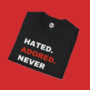 Folded black "HATED. ADORED. NEVER IGNORED." T-shirt by Red Devil Threads, ideal for Manchester United supporters.